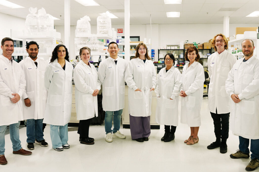Group photo of Cirsium Biosciences staff in lab with lab coats on